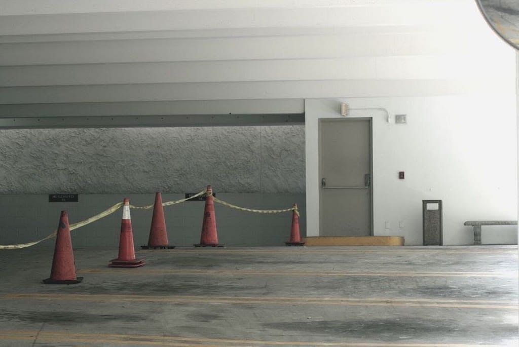 This is an image of an empty parking garage with five parking cones and tape. This image is used in the BPS Security Article titled, “When is it Okay for a Security Guard to Draw Their Gun?”