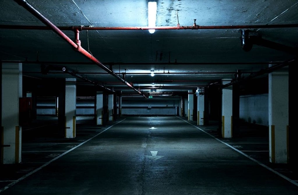 Image of a creepy basement of a parking garage. It's dimly lit. This image is used for a blog titled, "When Hiring a Security Firm, Carefully Read the Security Contract"