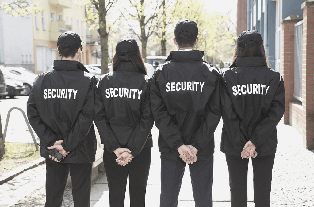 This is an image of four security guards, looking away from the camera (so we see their backs and the word “security” across the back of their shirts). This image is used in the BPS Security article titled, “What are the dangers of private security? Would you put your life at risk?”