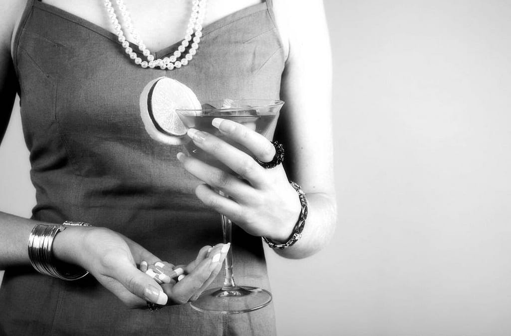 This is a closeup of a woman holding a cocktail in her left hand and a handful of pills in her right hand. This image is used in the BPS Security article titled, “Will Having Security Guards at Fraternity Parties Eliminate Drug and Sexual Abuse?”