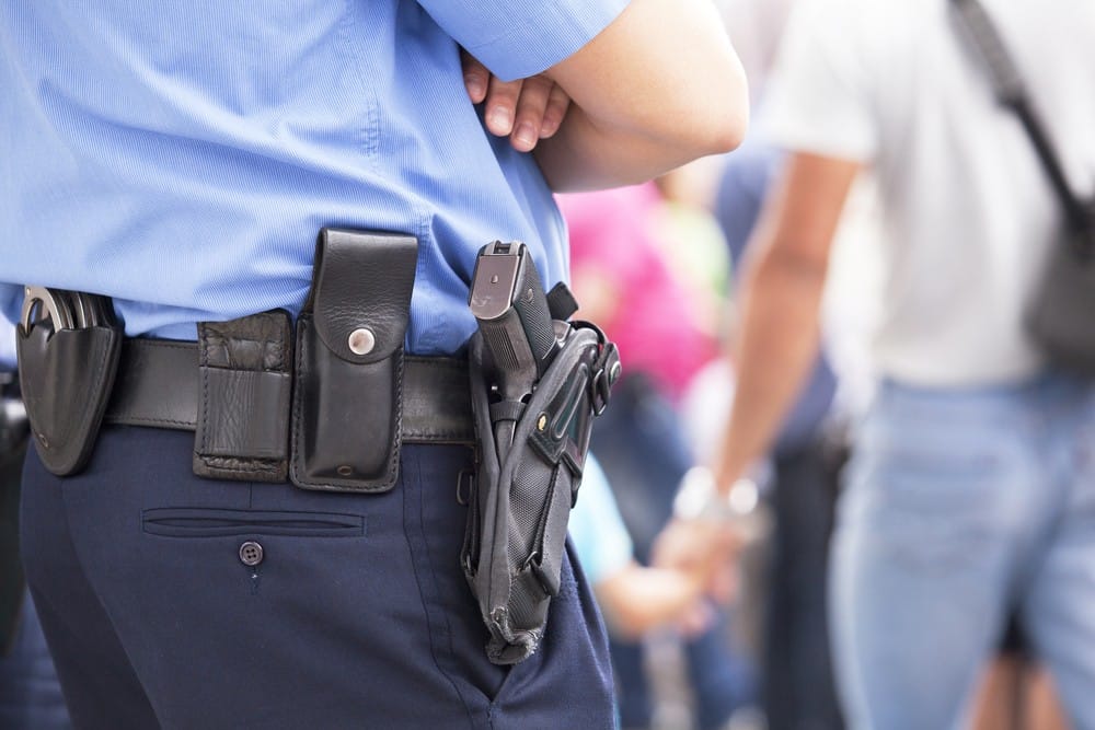 An armed guard can help reduce liability but there is more to consider-- picture of a holstered weapon on a guard's hip