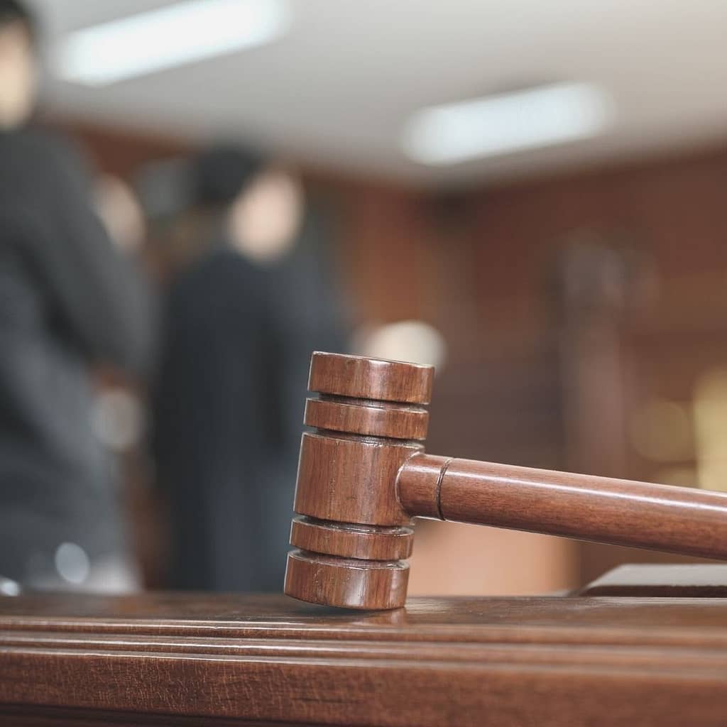 This is a closeup image of a judge's gavel with a blurry court scene in the background. This image is used in a BPS Security blog discussing whether or not Is it okay for a Security Guard to Touch You?
