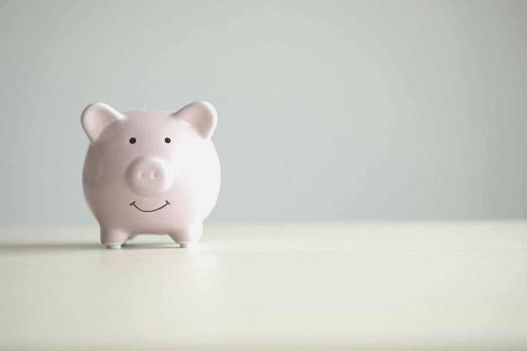 This is and image of a piggy bank on a light wooden table in front of a grey wall. This image is used in the BPS Security Blog, “Why Every Security Company Should Use GPS”, showcasing how GPS can save companies money.