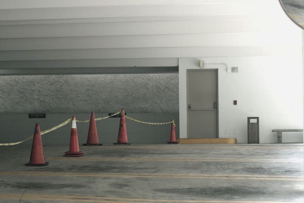 This is an image of an empty parking garage with five parking cones and tape. This image is used in the BPS Security Article titled, “When is it Okay for a Security Guard to Draw Their Gun?”