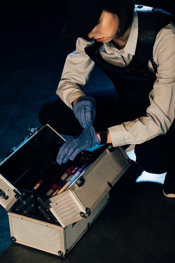 A PI putting her gloves on next to her kit to prepare for a criminal investigation
